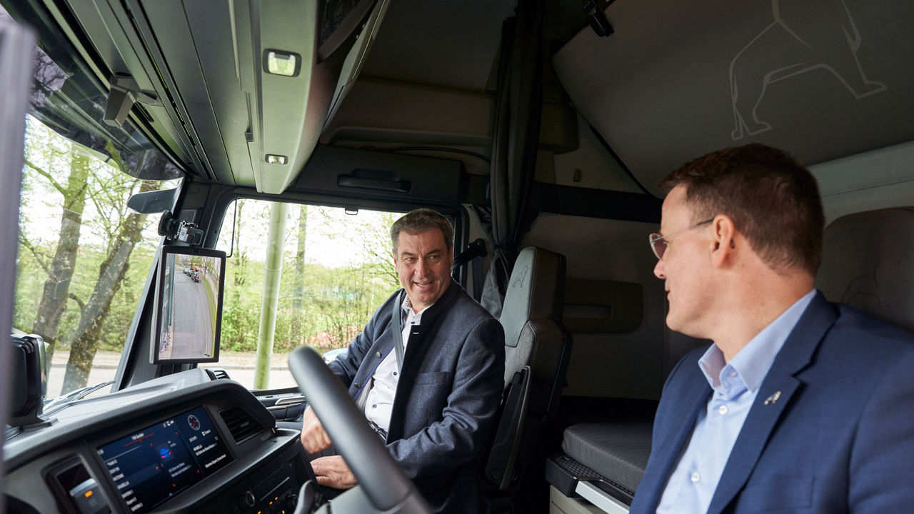 Closeup of Dr Markus Söder and Alexander Vlaskamp in the cockpit of a truck. 