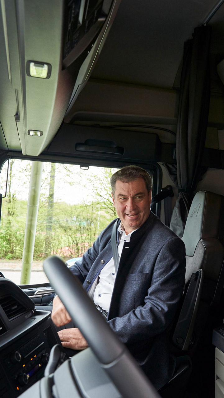 Closeup of Dr Markus Söder and Alexander Vlaskamp in the cockpit of a truck. 
