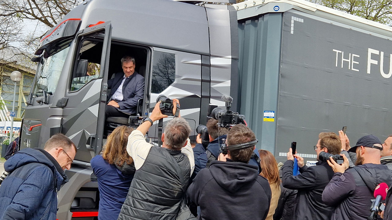 Group of journalists in front of a truck in which Dr. Markus Söder is sitting. 
