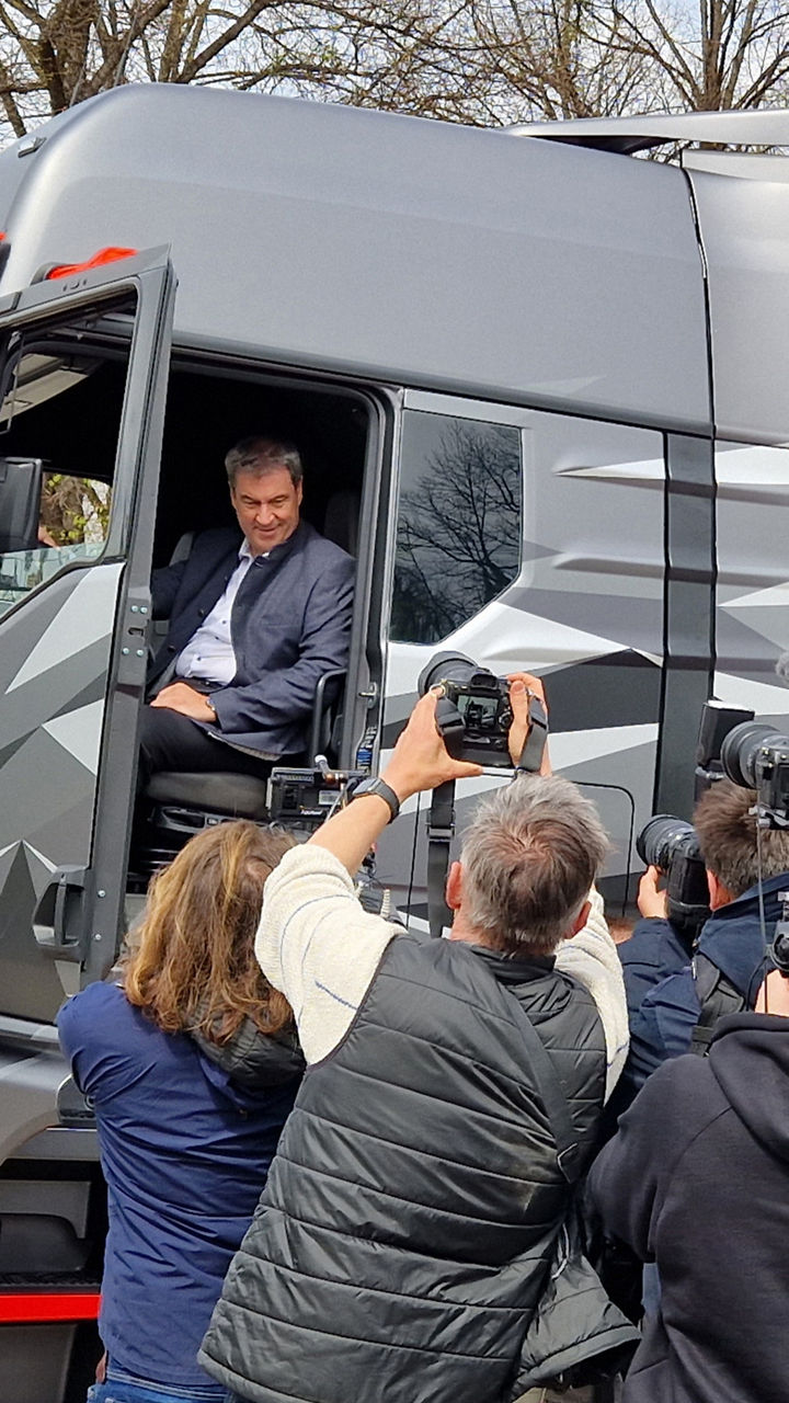 Group of journalists in front of a truck in which Dr. Markus Söder is sitting. 