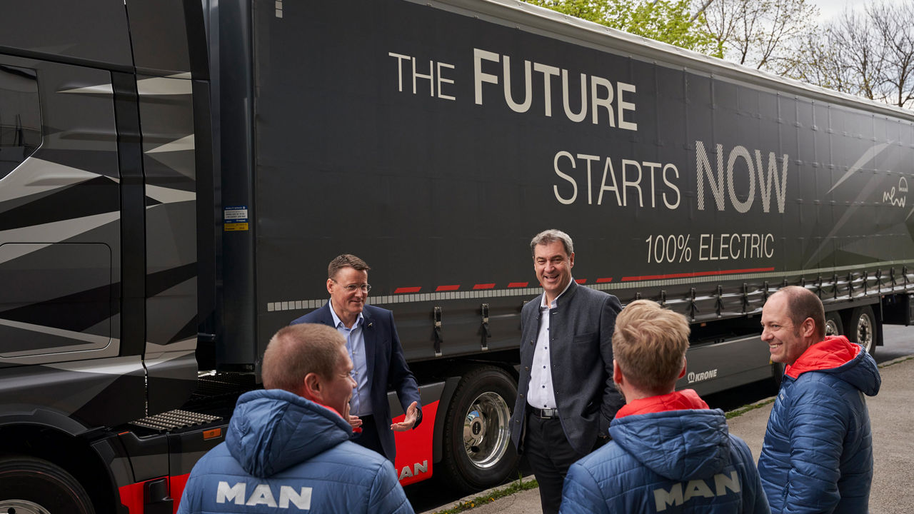 Dr Markus Söder and Alexander Vlaskamp are standing in front of a truck with three other men. 