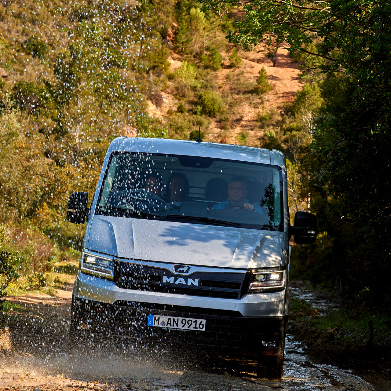 A MAN van driving off-road through a stream.