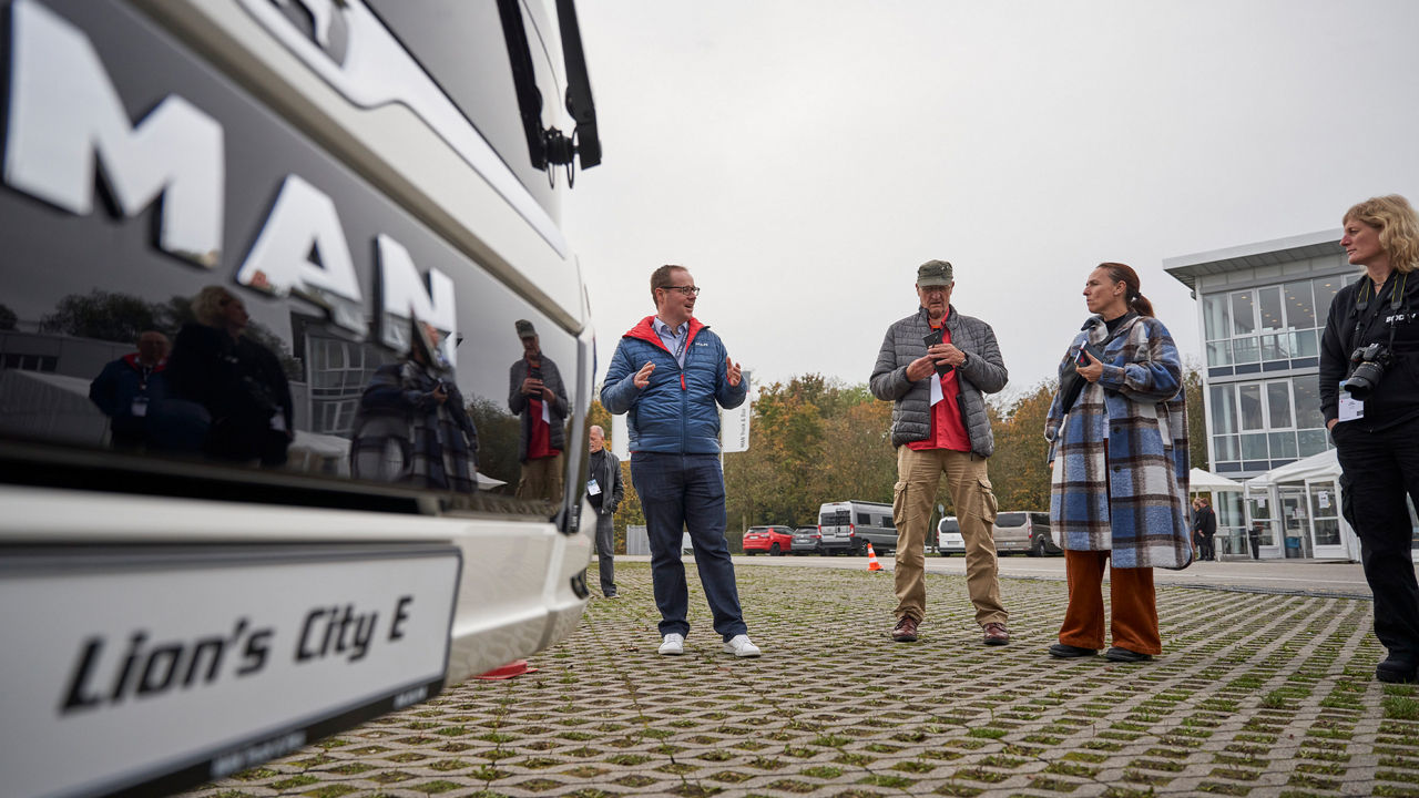 Journalisten und Journalistinnen stehen auf dem MAN Testgelände und schreiben etwas auf