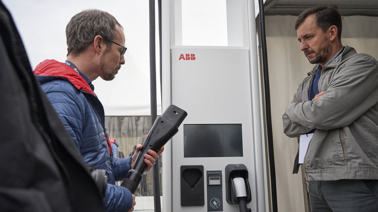 Ein Mann hält den Stecker von einer Ladesäule in der Hand