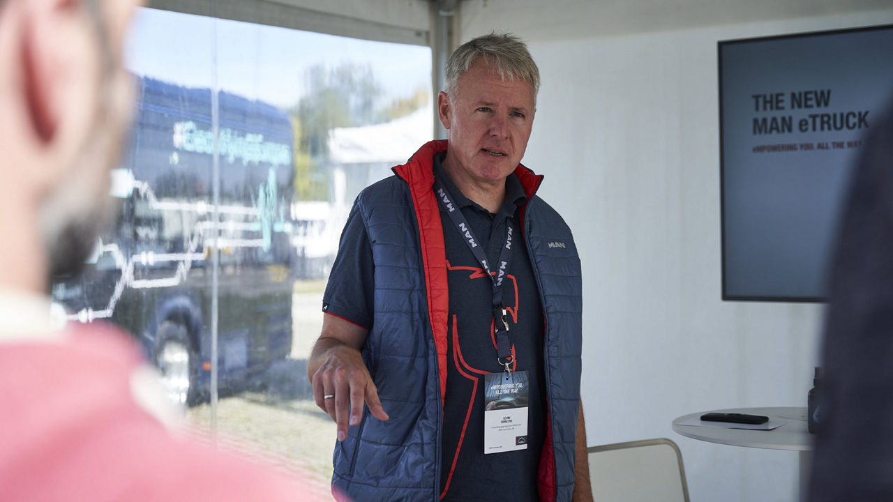 Achim Demattio steht vor einer Leinwand und erklärt etwas