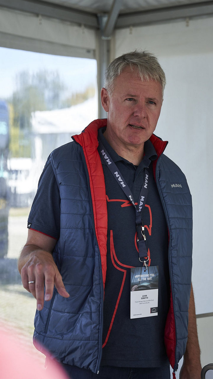 Achim Demattio steht vor einer Leinwand und erklärt etwas