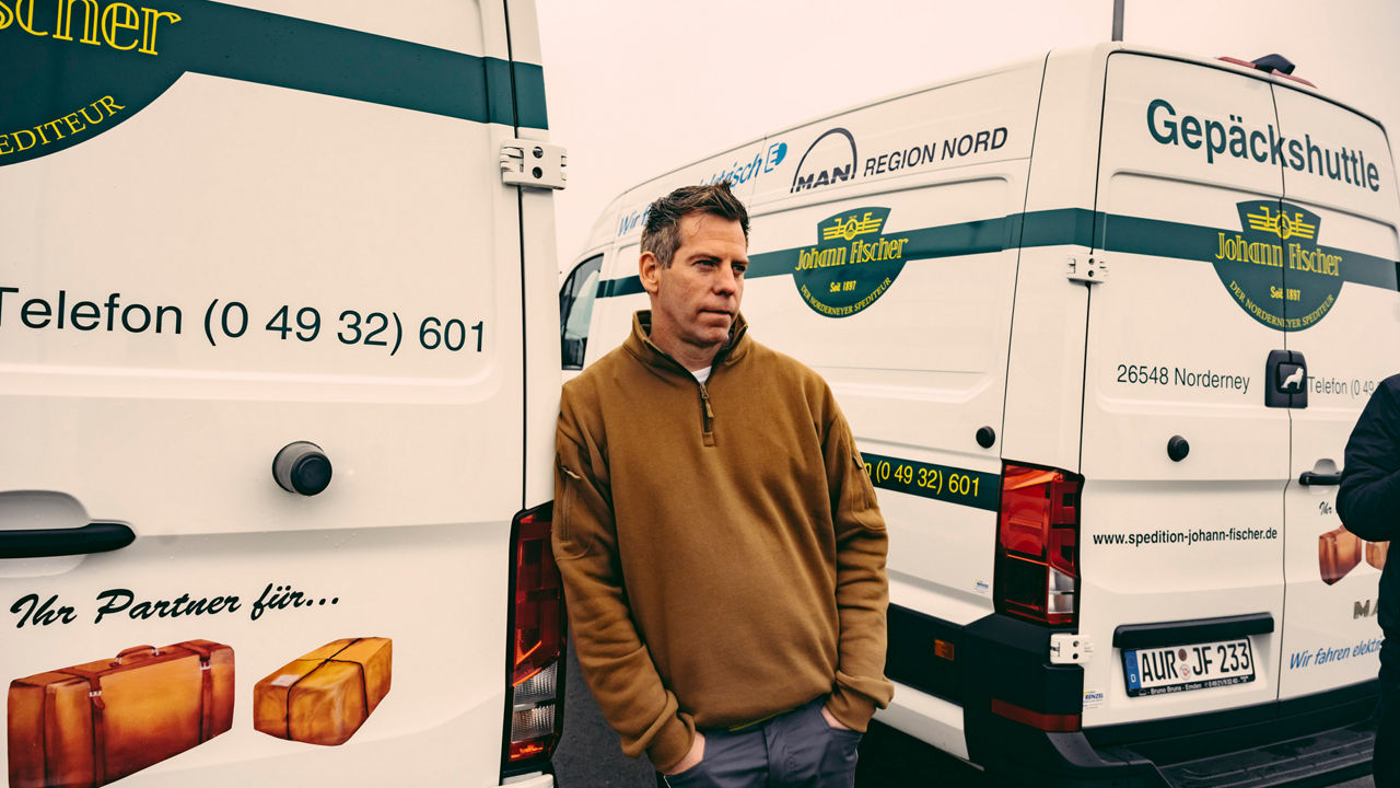 Portrait von Sven Große-Hohnacker, der an einen Transporter lehnt. 