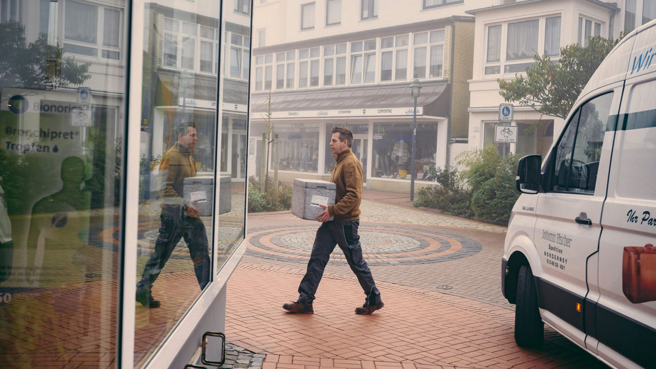 Speditionsfahrer Sven Große-Hohnacker trägt eine Box vom Van zu einem Haus. 