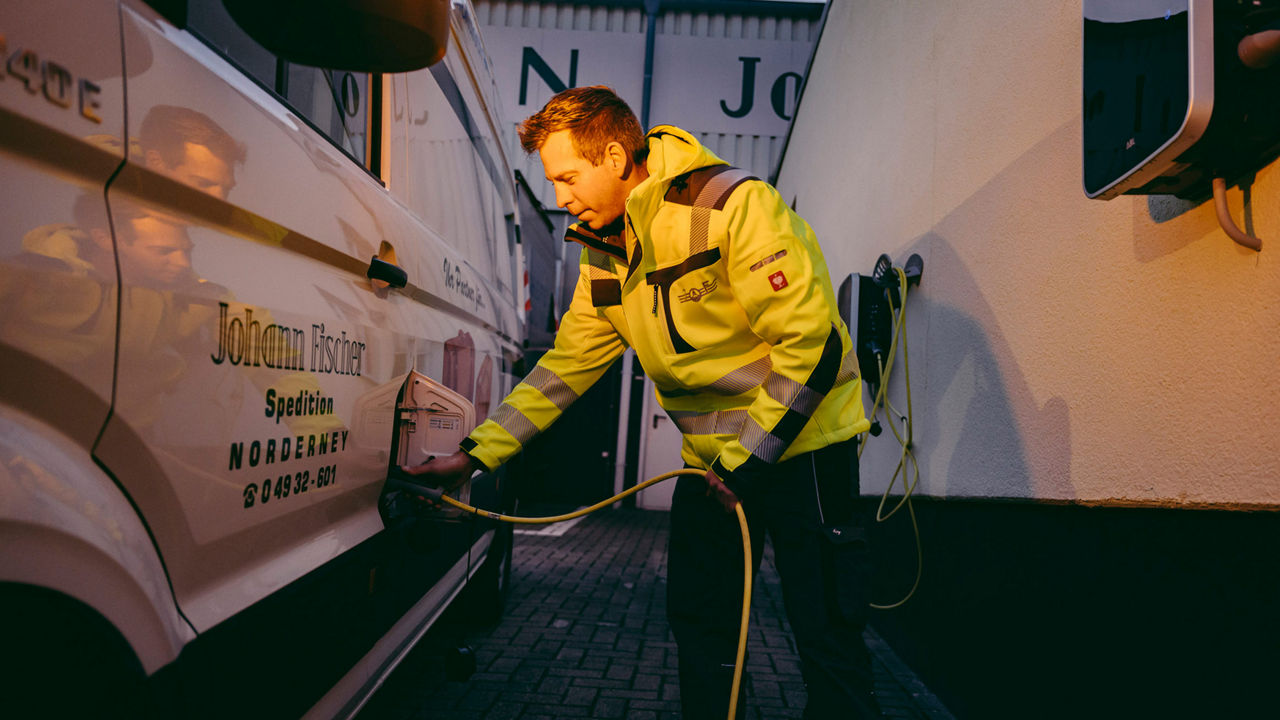 Aufnahme einer Person, die ein Speditionsfahrzeug an die Ladestation anschließt. 