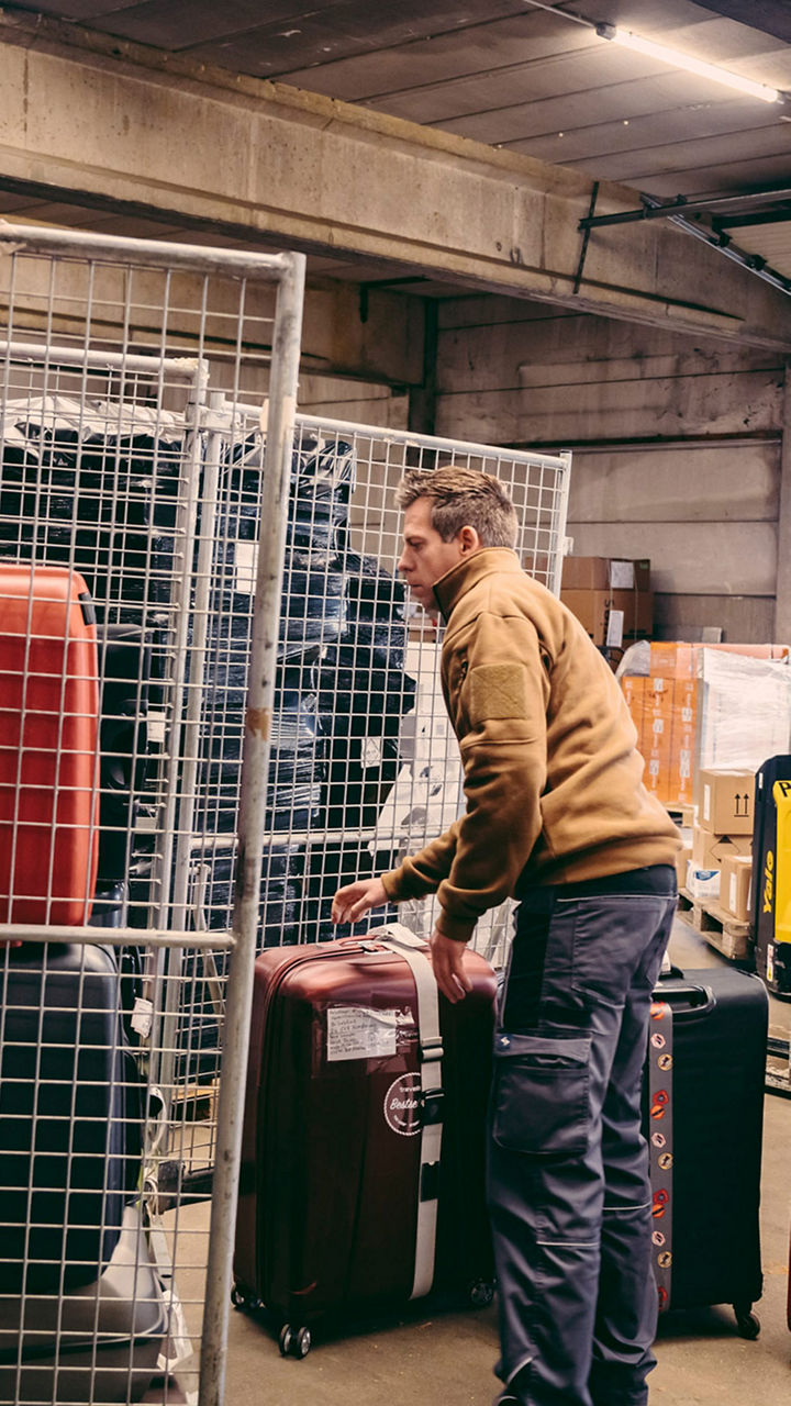 Große-Hohnacker steht in einem Lagerraum, in dem Koffer untergebracht sind. 