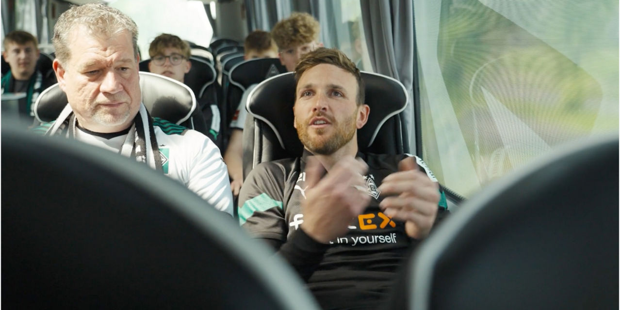 Ein Mann sitzt gestikulierend in einem Reisebus