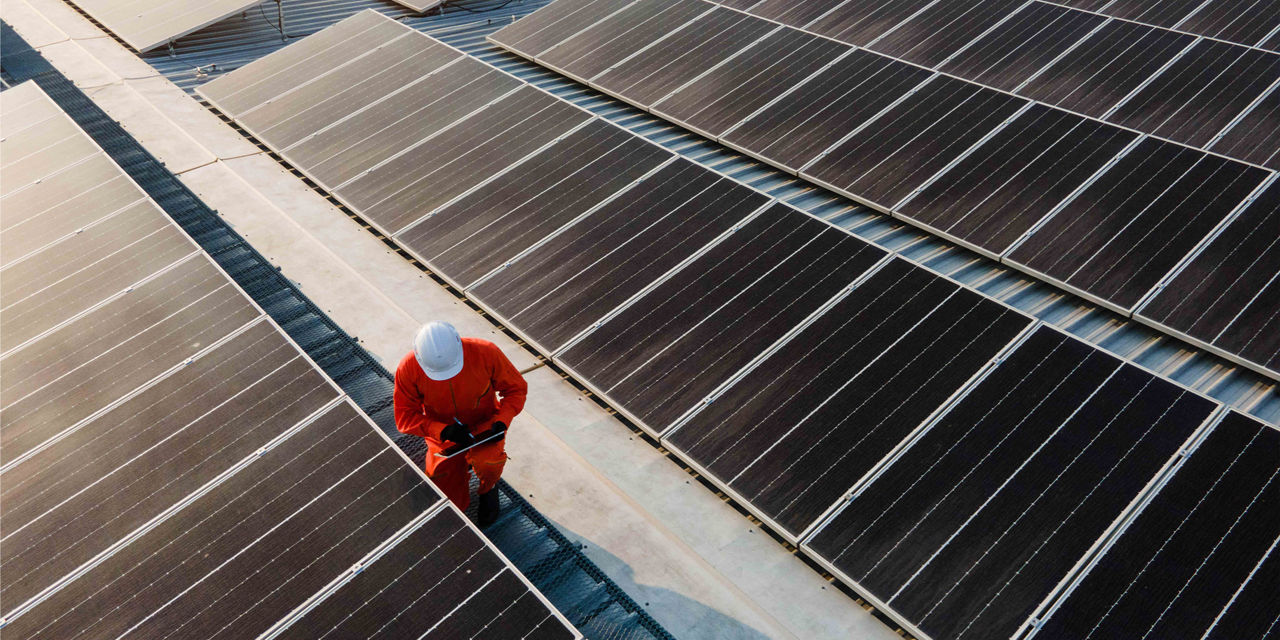 A man in work clothes walking along an array of solar panels