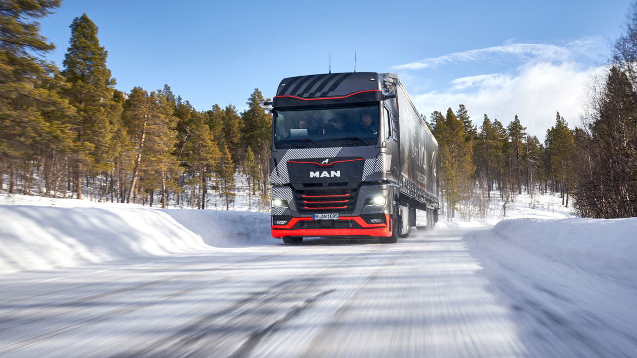 A MAN truck drives through a winter landscape. 