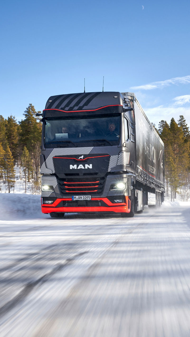 A MAN truck drives through a winter landscape. 