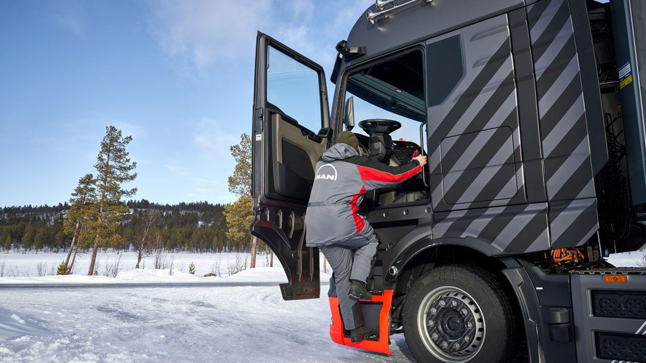 A man gets into a truck. In the background a winter landscape. 