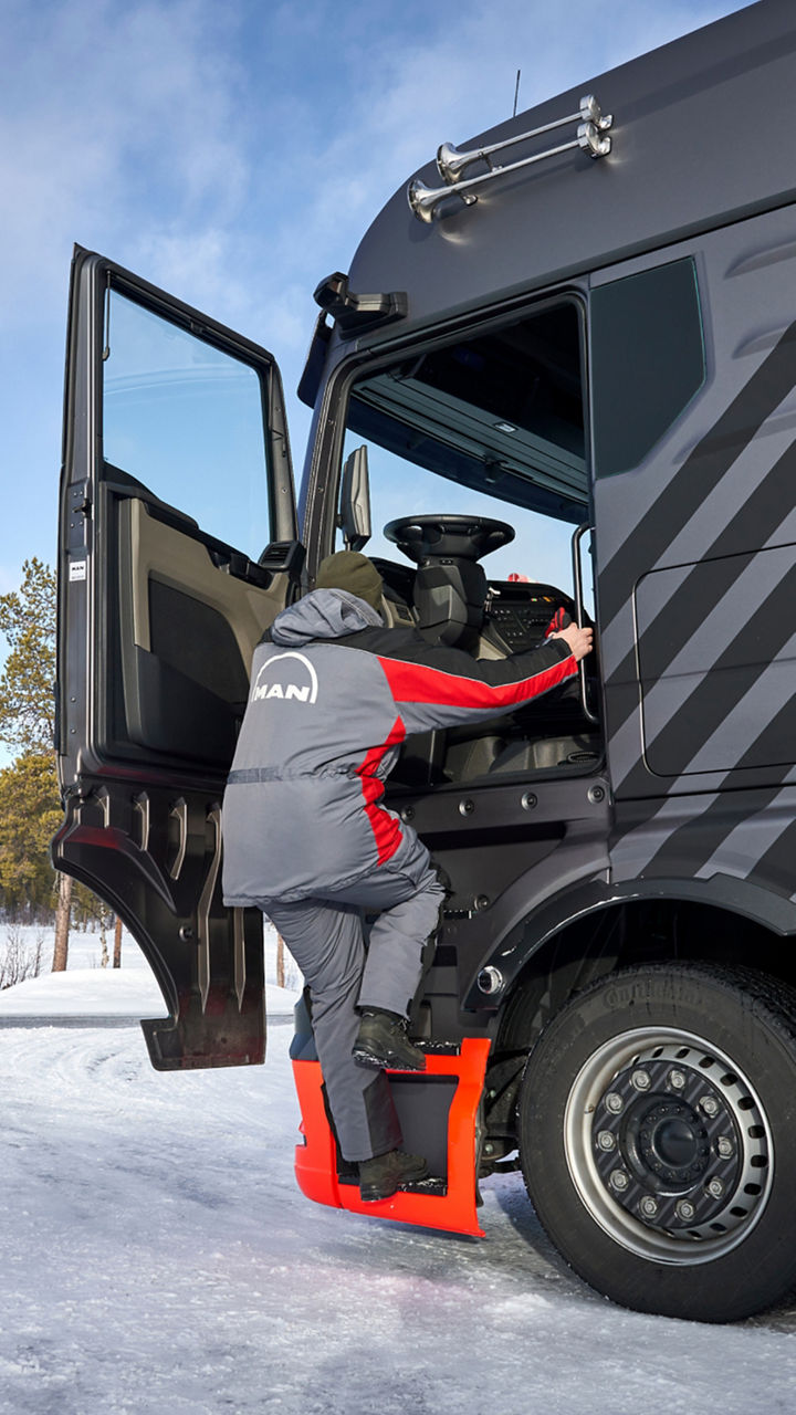A man gets into a truck. In the background a winter landscape. 
