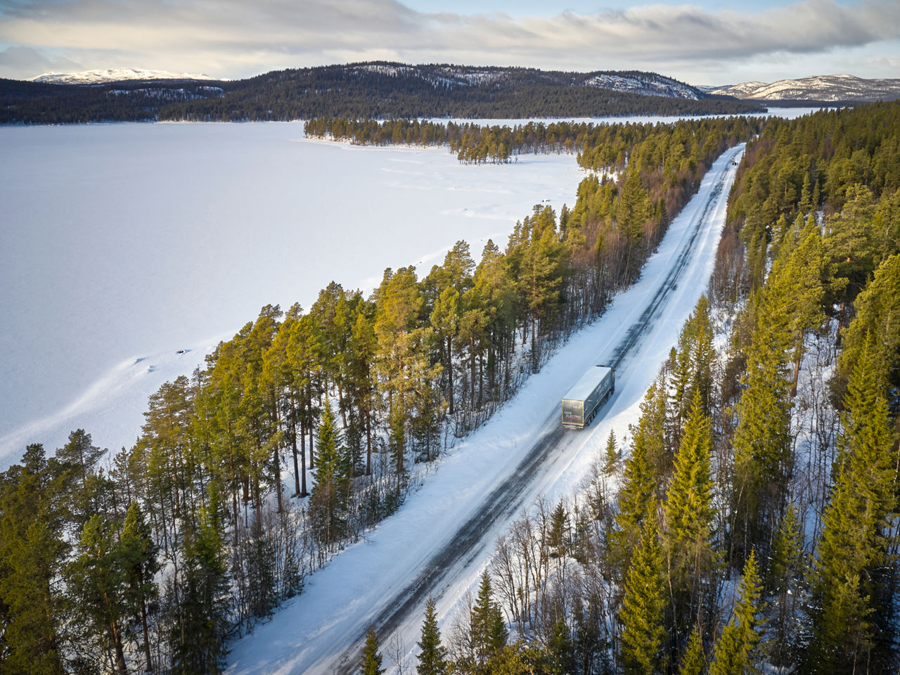 A MAN truck drives through a vast winter landscape. 
