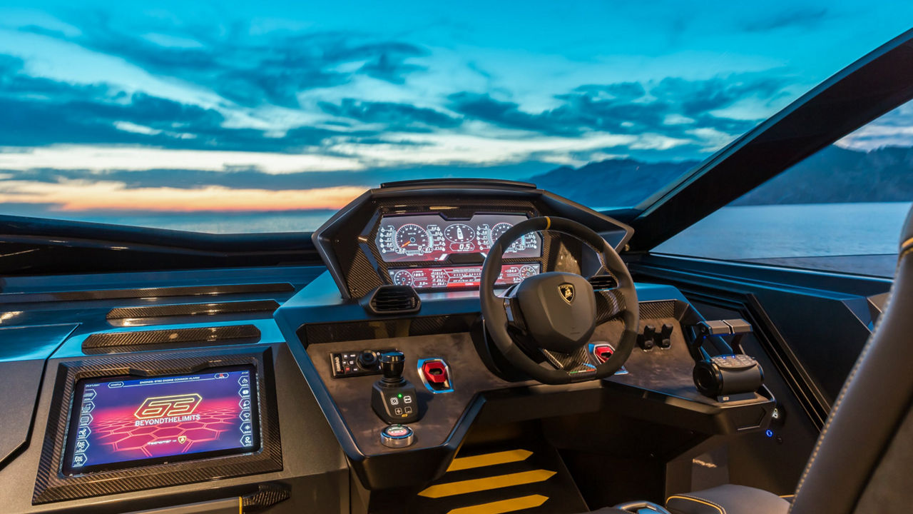 Blick auf das Steuersystem einer Yacht in der Steuerkabine, ein Abendhimmel erstreckt sich hinter der Glasscheibe. 