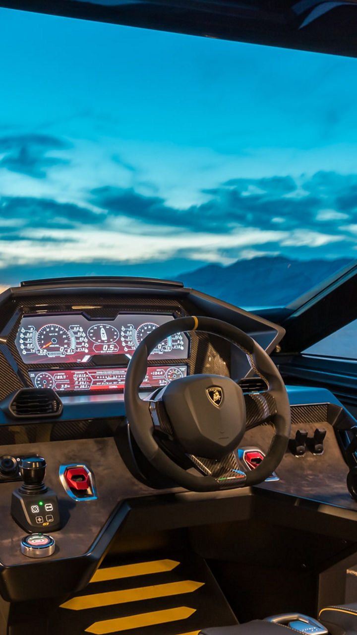 Blick auf das Steuersystem einer Yacht in der Steuerkabine, ein Abendhimmel erstreckt sich hinter der Glasscheibe. 