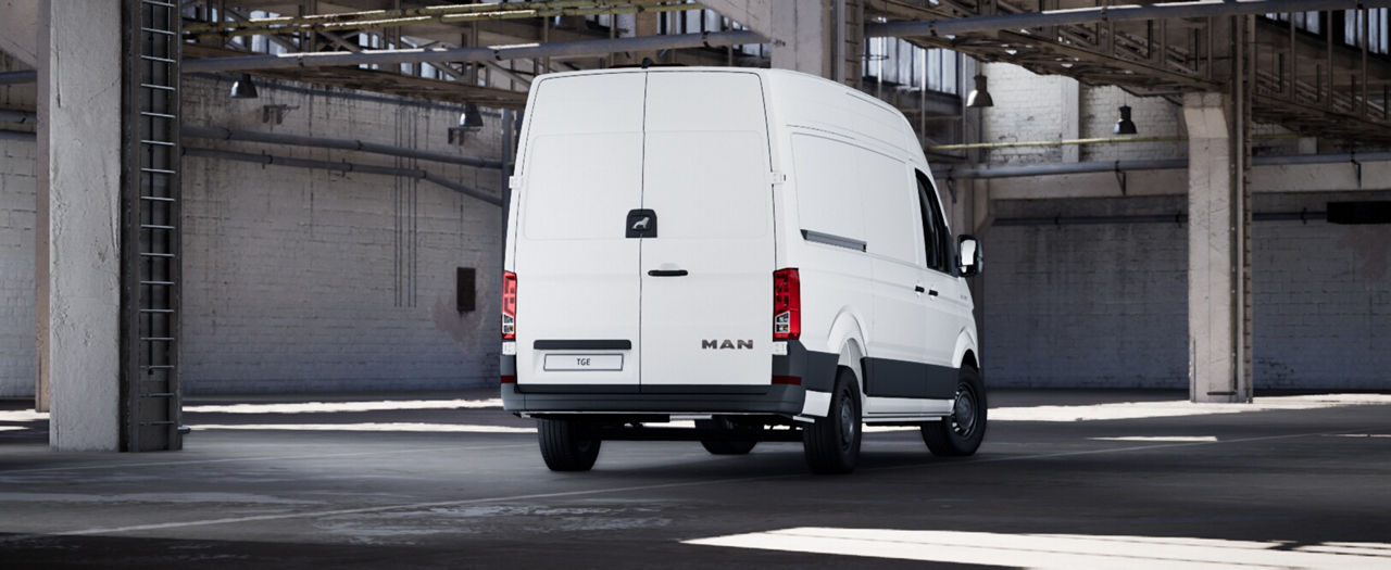 Rear view of a white MAN van with closed rear doors inside an industrial hall.
