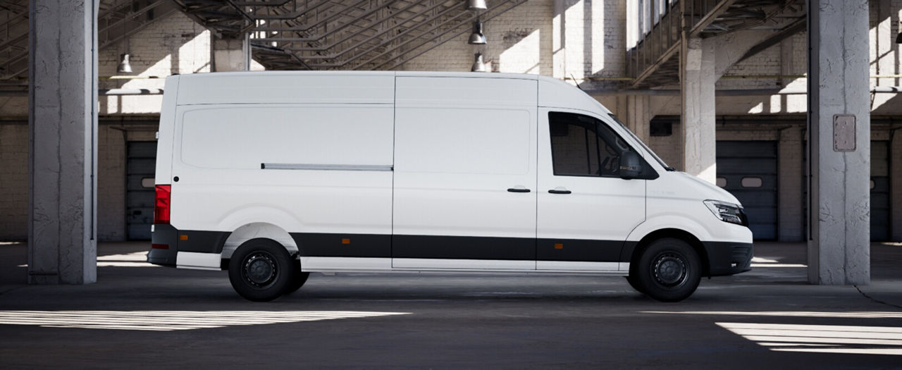 Full left-side profile of a white MAN panel van in an industrial building