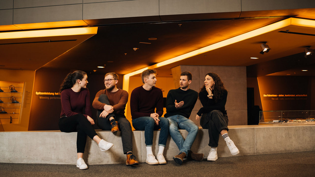 Eine Gruppe junger Leute sitzt auf einer Stufe und unterhält sich