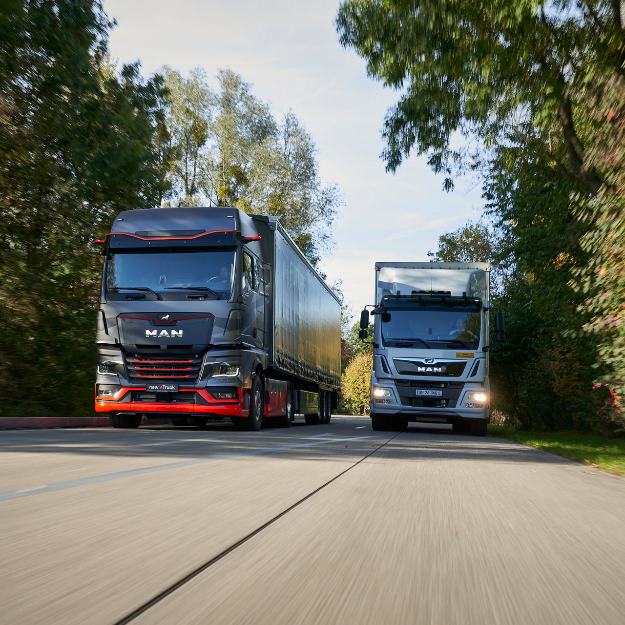 Two MAN eTrucks driving on a road