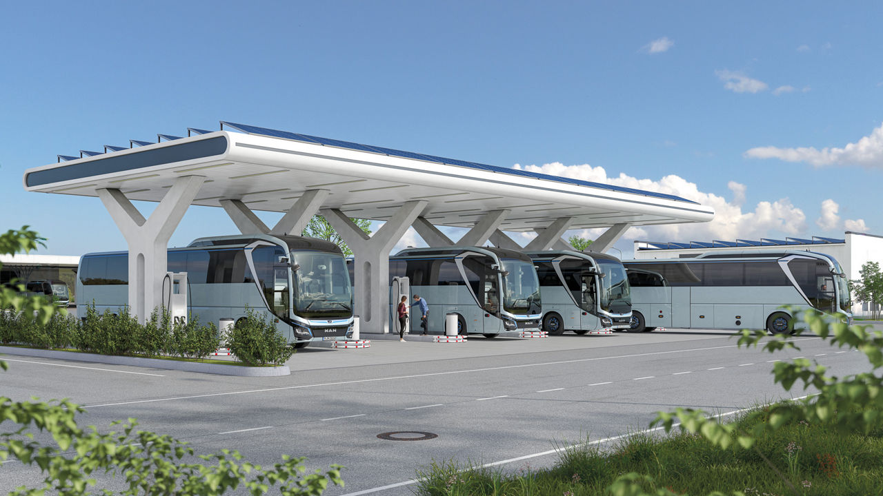 Mehrere MAN-Reisebusse stehen unter einem modernen Lade- und Überdachungssystem auf einem Parkplatz.