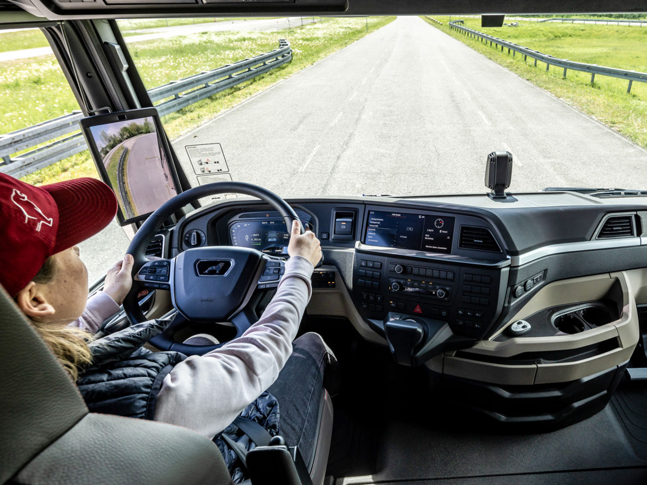 Fahrerin lenkt MAN Truck auf leerer Landstraße, Innenraum-Perspektive