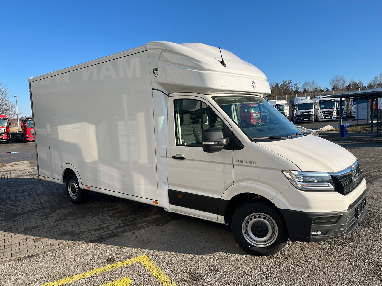 Side view of a white MAN high-roof delivery van in a large indoor hall