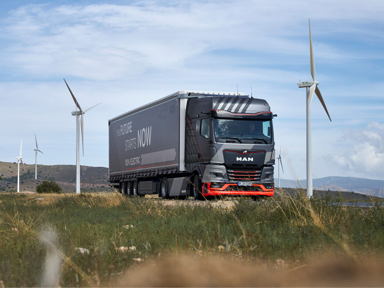 MAN Truck driving through landscape with wind turbines in the background