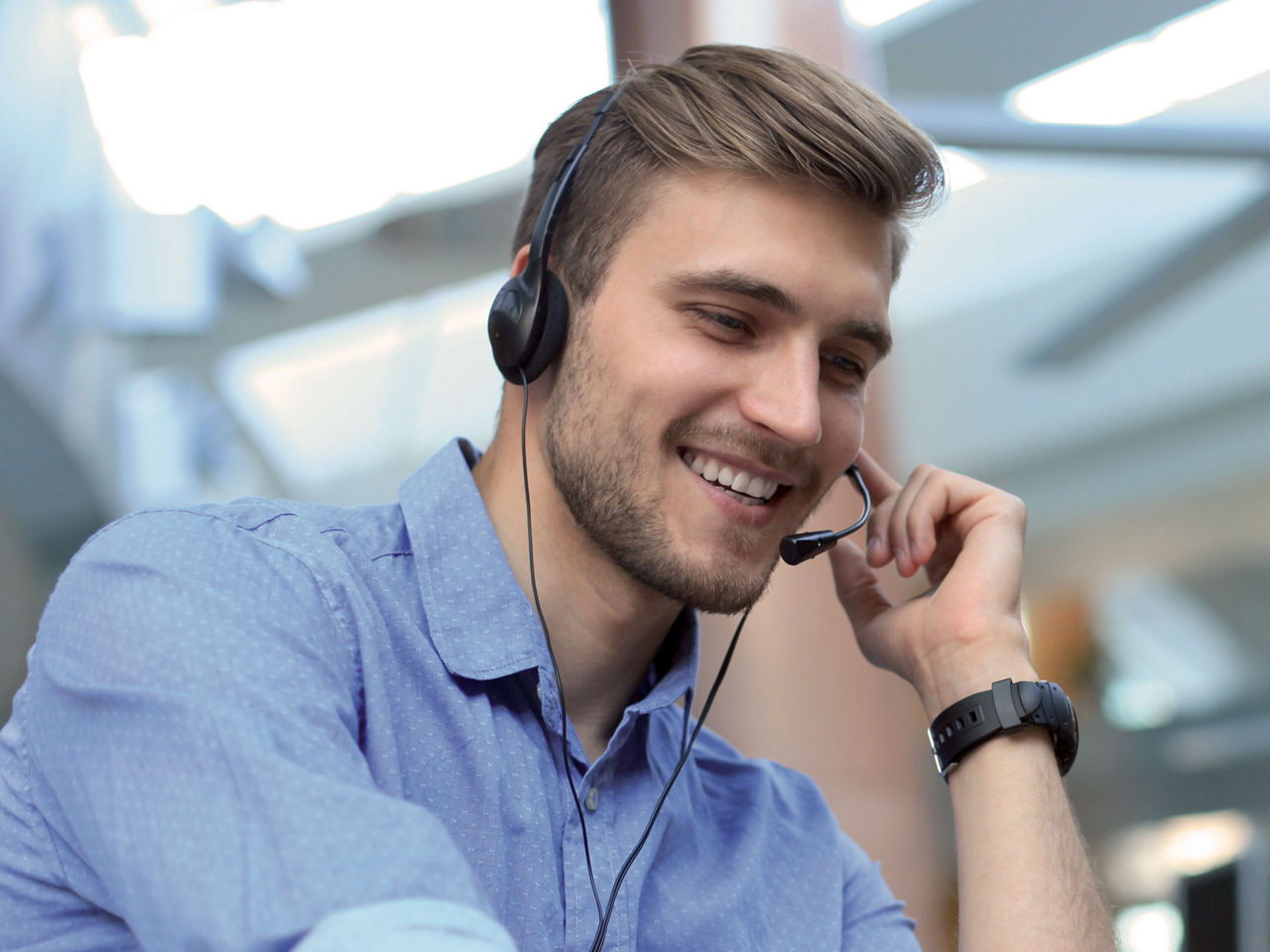 Smiling friendly handsome young male call centre operator.