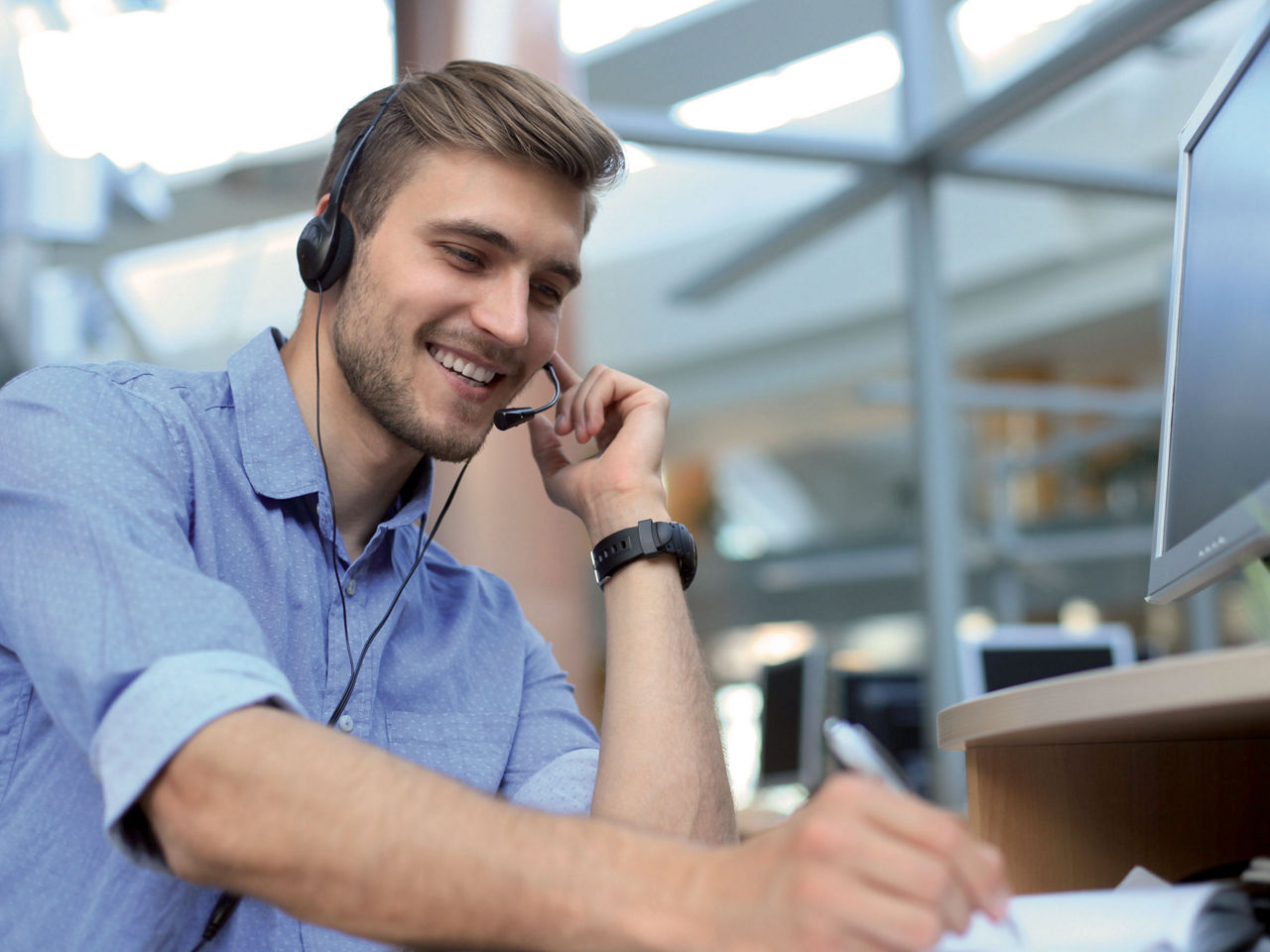 Smiling friendly handsome young male call centre operator.